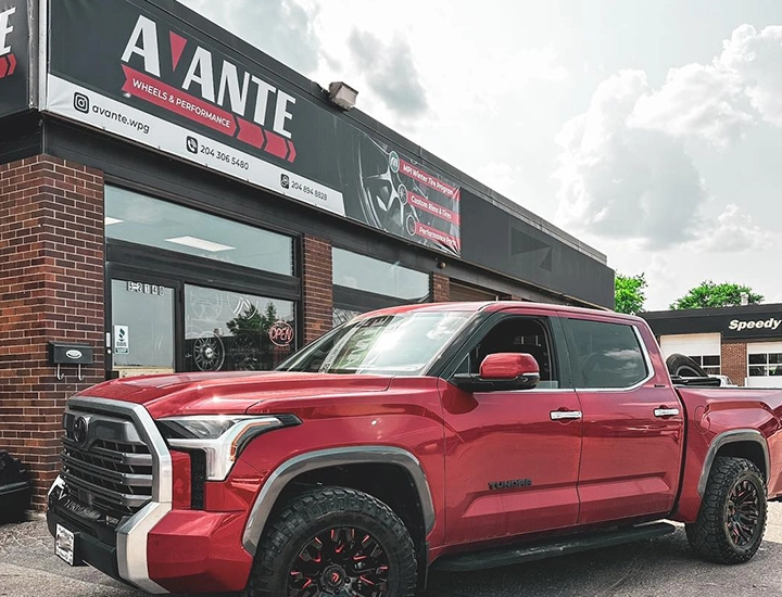 A red truck parked in front of a building, showcasing its vibrant color against the urban backdrop.